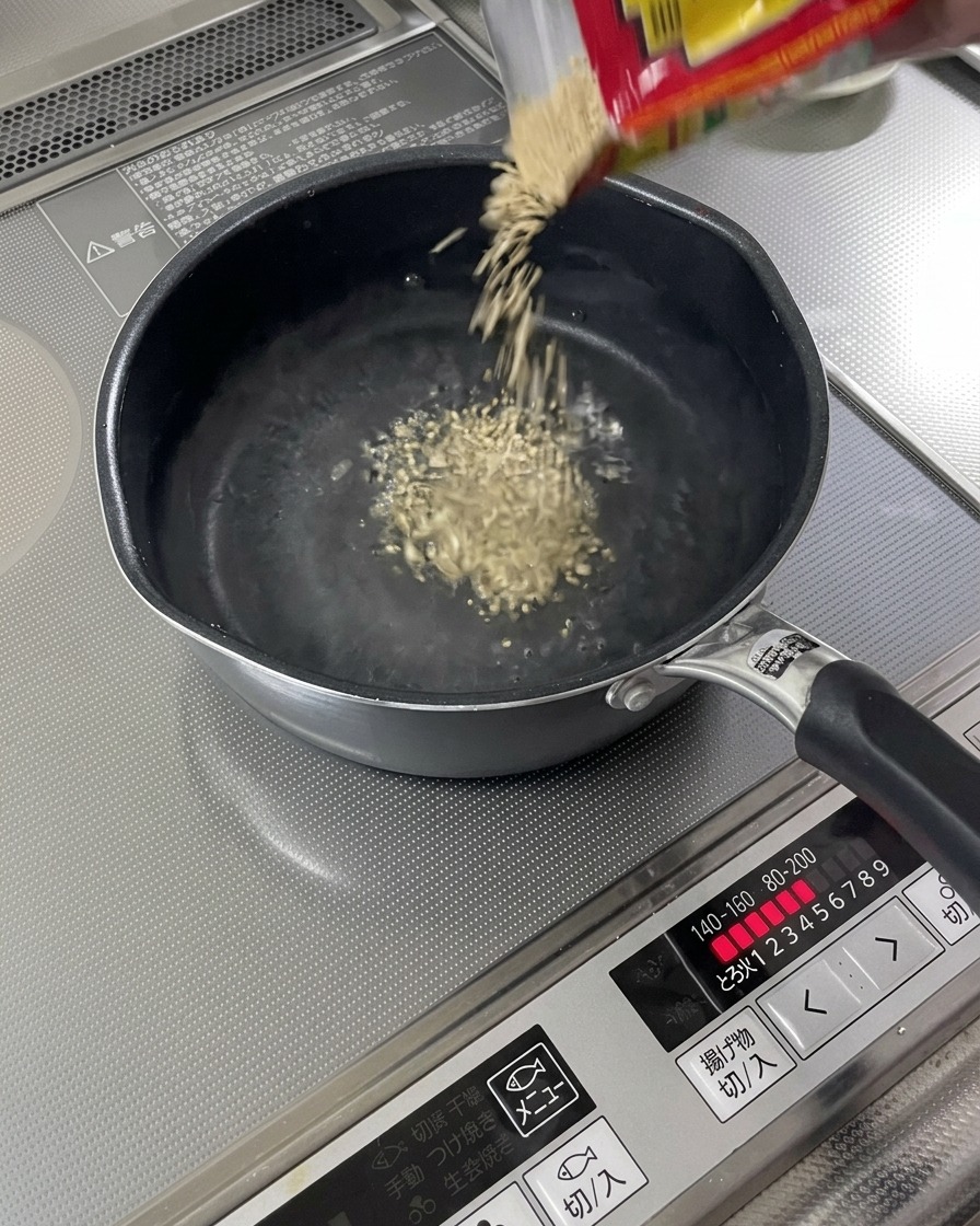 Roasted sesame seeds falling into a pot of simmering liquid.