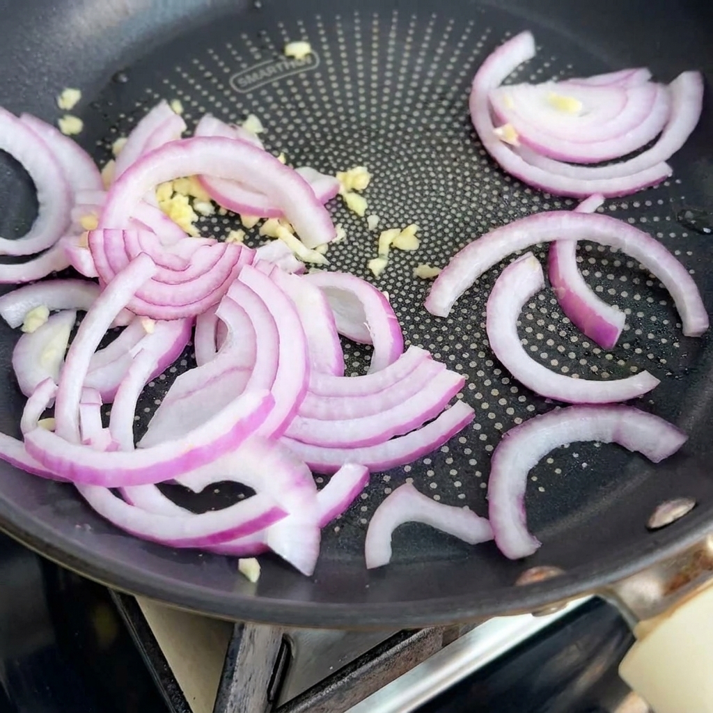Onions and garlic sautéing in a pan, releasing fragrance.