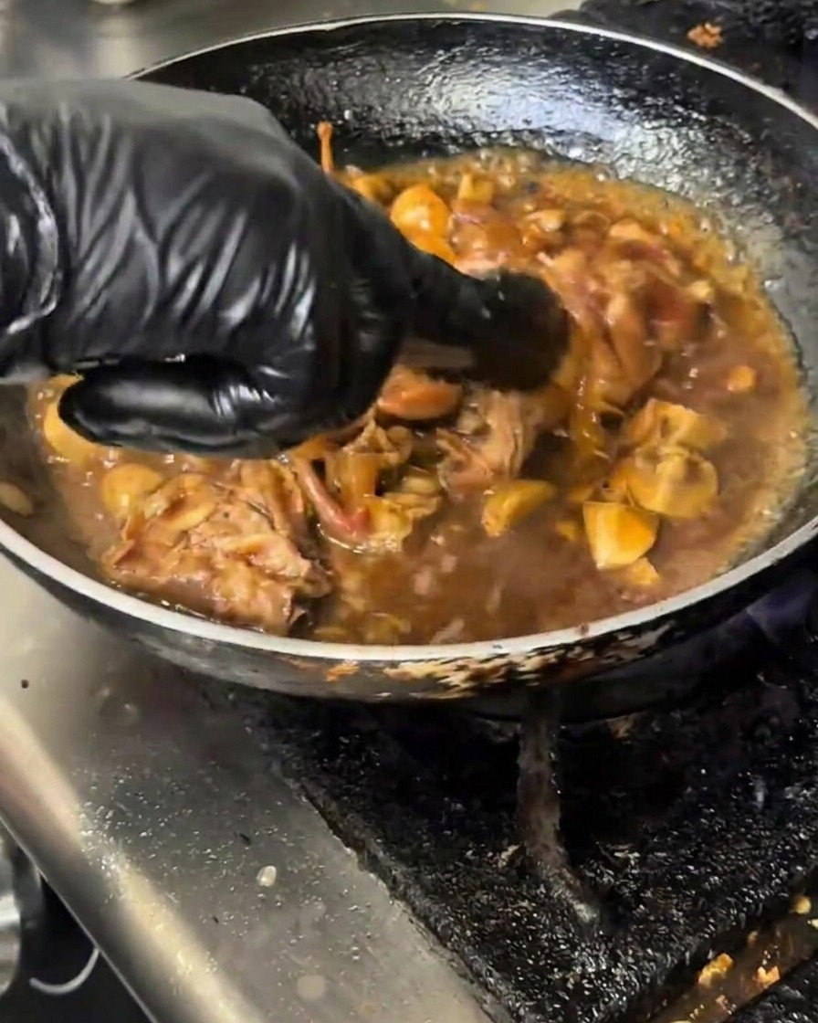 A ladle or measuring cup pouring a milky starch slurry into a simmering pan of beef and mushroom stir-fry.