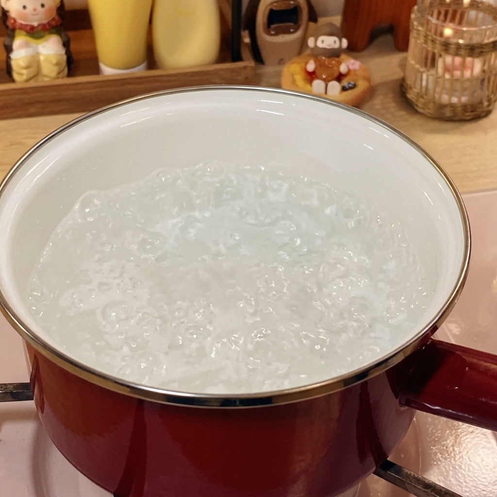 Frozen beef rolls submerged in boiling water in a red pot.