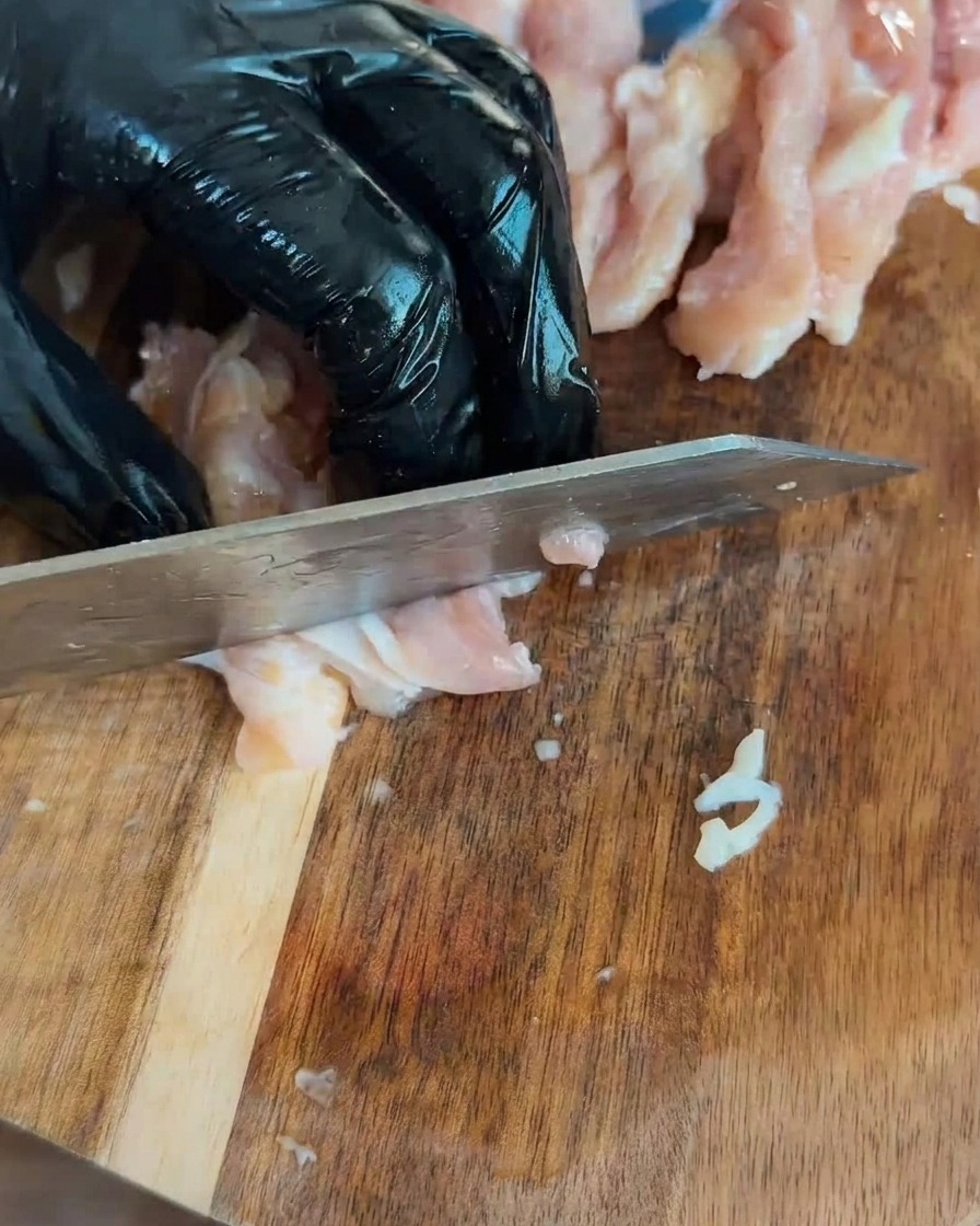 Diced raw chicken pieces arranged on a wooden cutting board.
