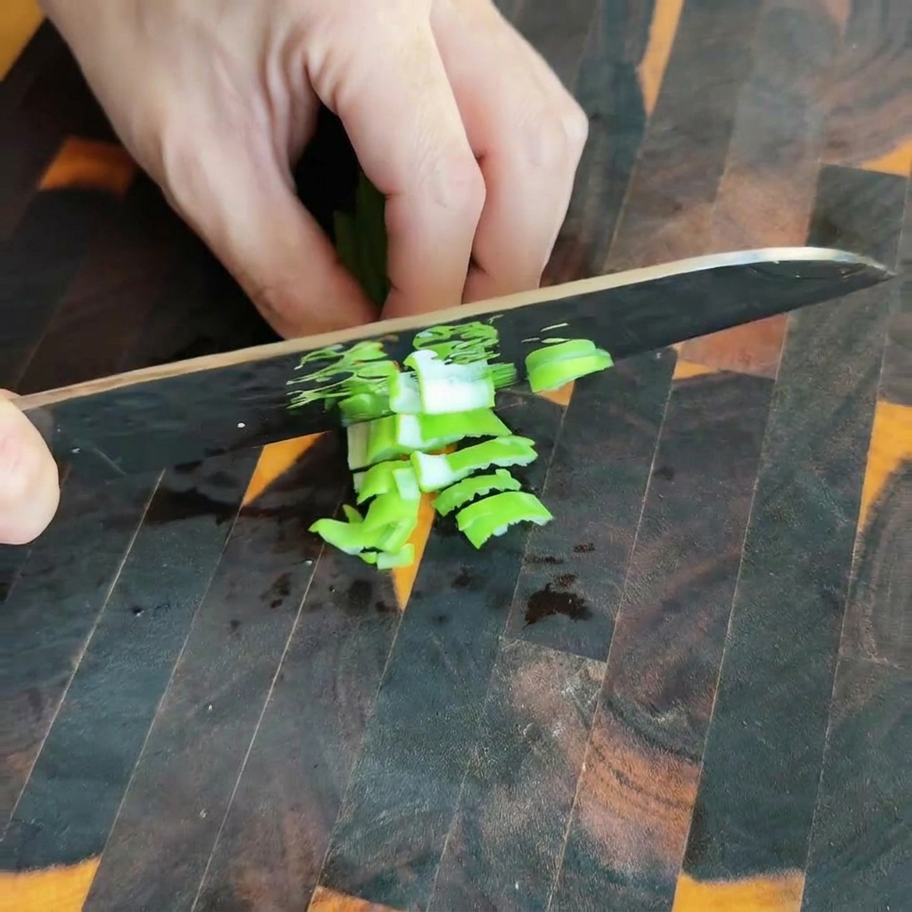 Pickled mustard greens being diced on a wooden cutting board.