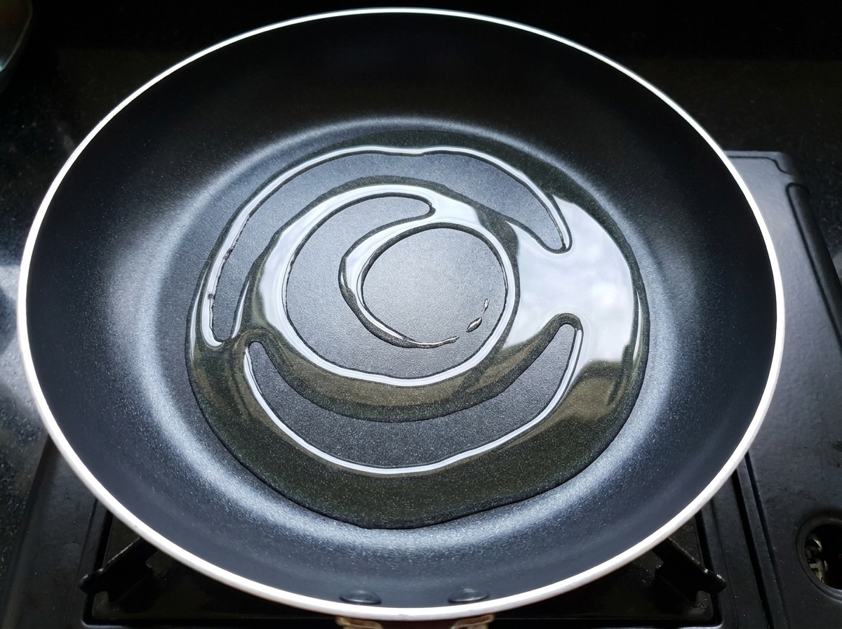 Marinated chicken pieces being added to a hot, oiled frying pan.