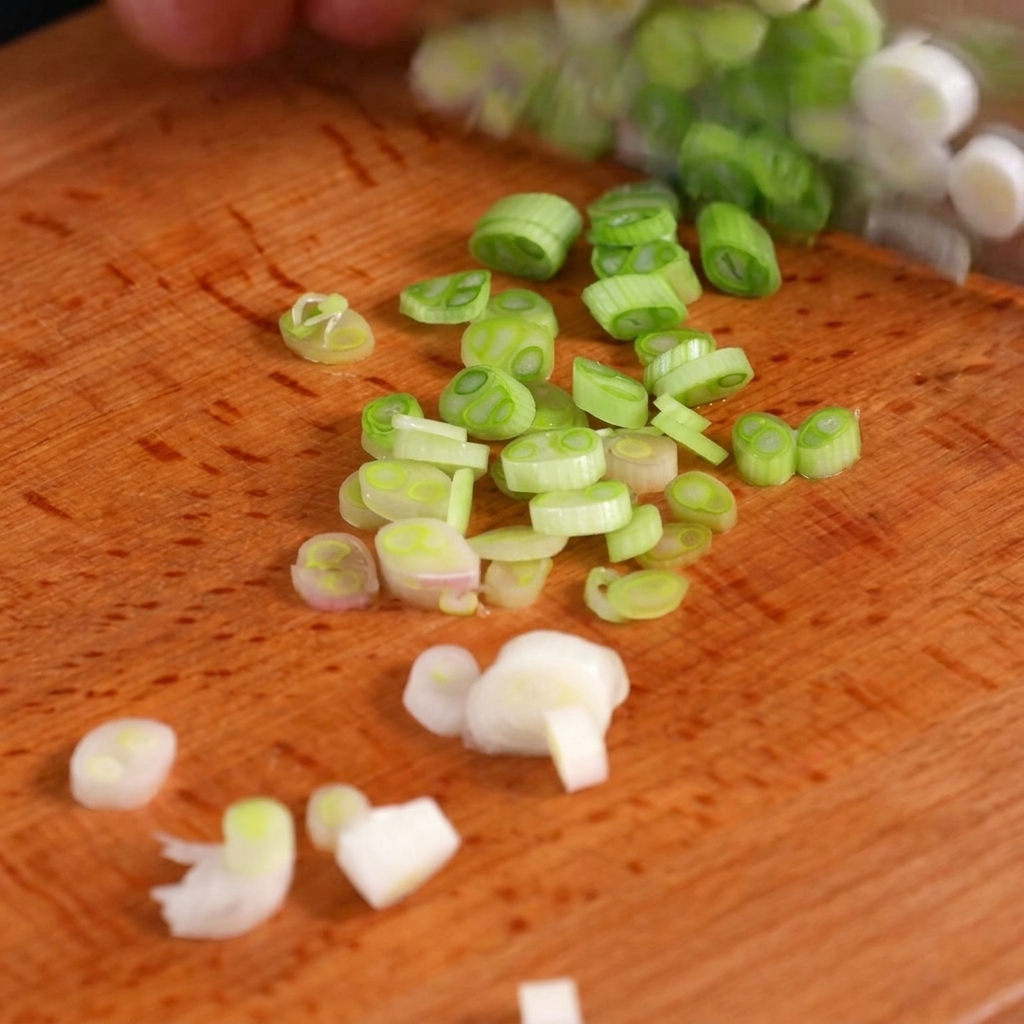 Fresh green onions finely sliced into rings on a wooden cutting board.