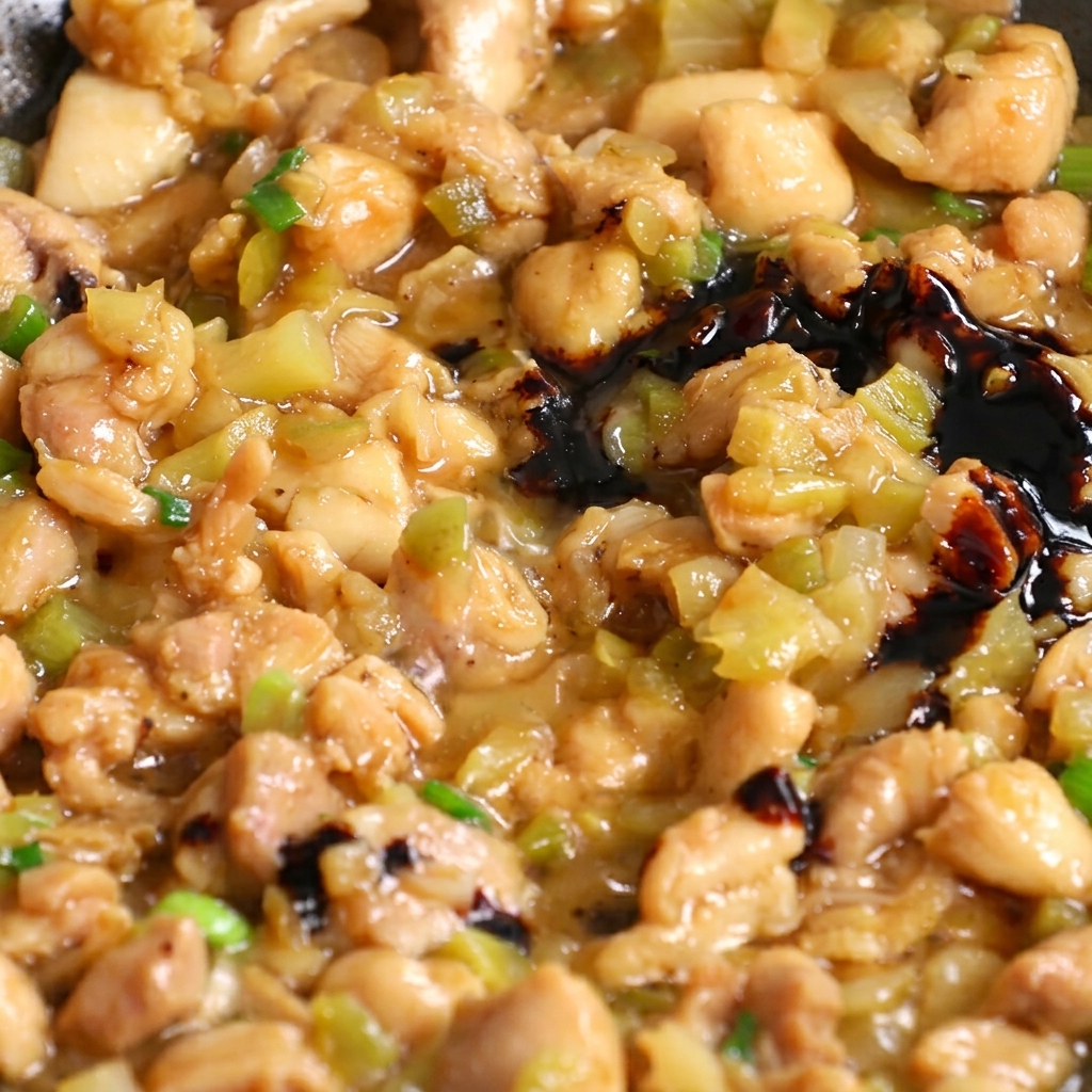 Dark soy sauce being poured into a skillet with stir-frying chicken and vegetable mixture.