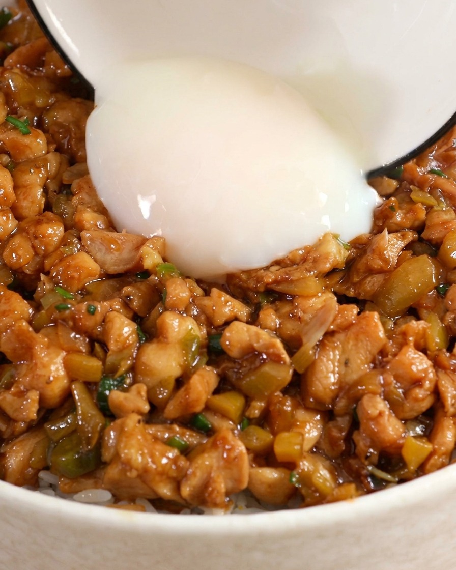 A soft-boiled onsen egg being added to the center of a chicken and rice bowl.