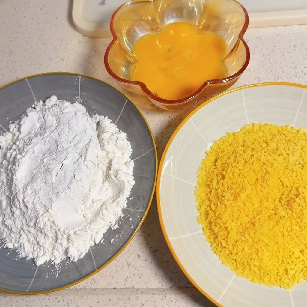 A raw pork slice being pressed into a plate of dry white cornstarch.