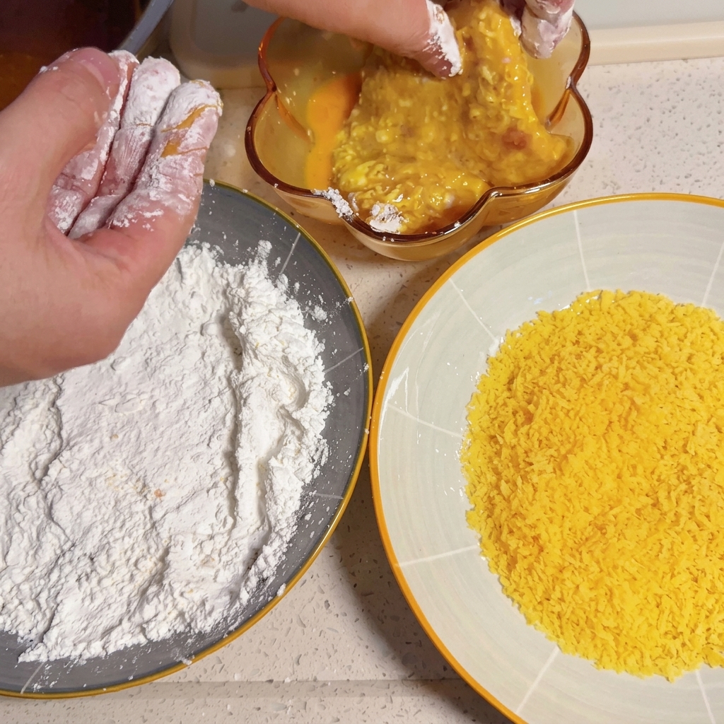 A cornstarch-coated pork slice being submerged in a bowl of beaten egg.