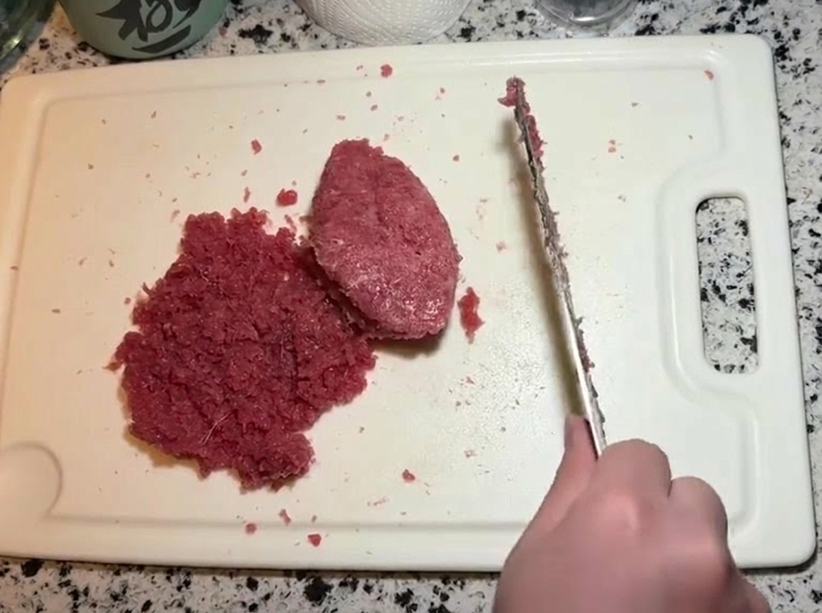 A knife chopping and folding a mayonnaise-infused tuna paste together with a pile of plain minced raw tuna.