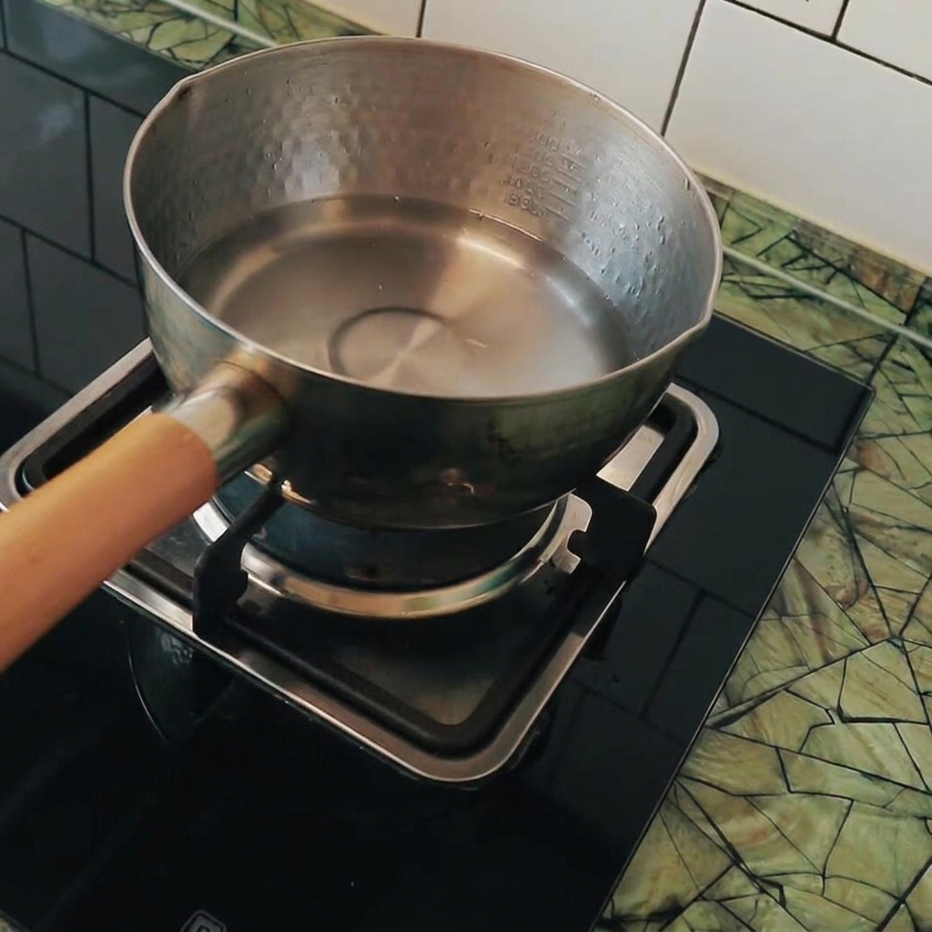Tofu cubes being added to a pot of boiling water.