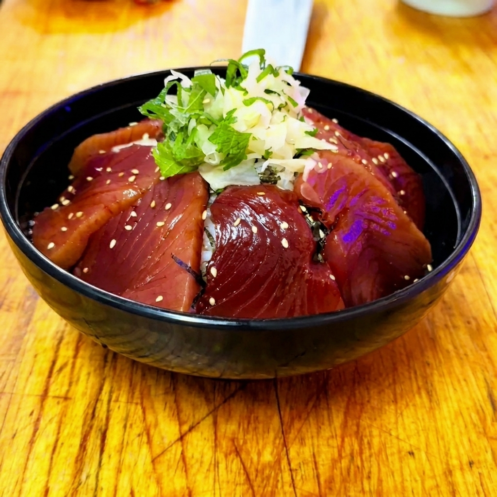 A finished Zuke Don rice bowl with marinated tuna, ginger, shiso, and a light dusting of white sesame seeds.
