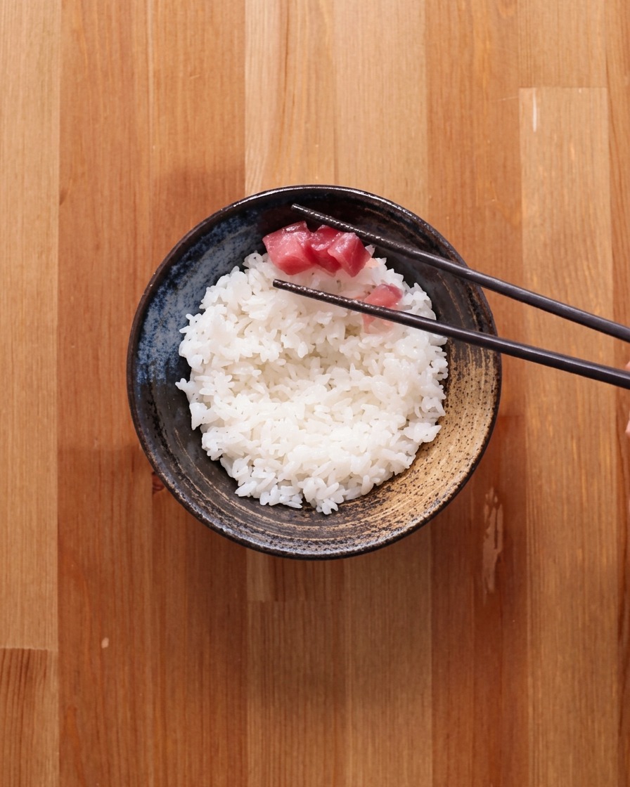 A bowl of white rice partially covered with a layer of cubed raw tuna.