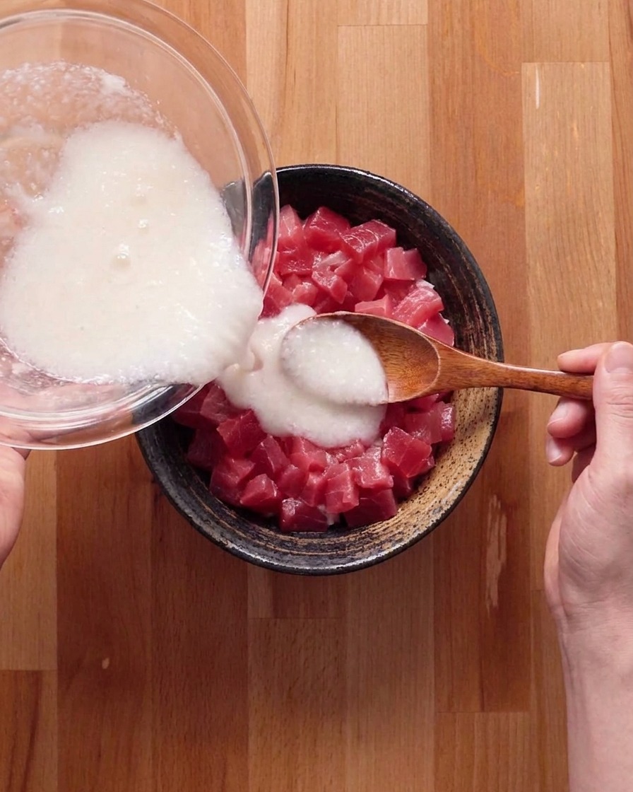 The white yam and broth mixture being drizzled over the tuna and rice bowl.