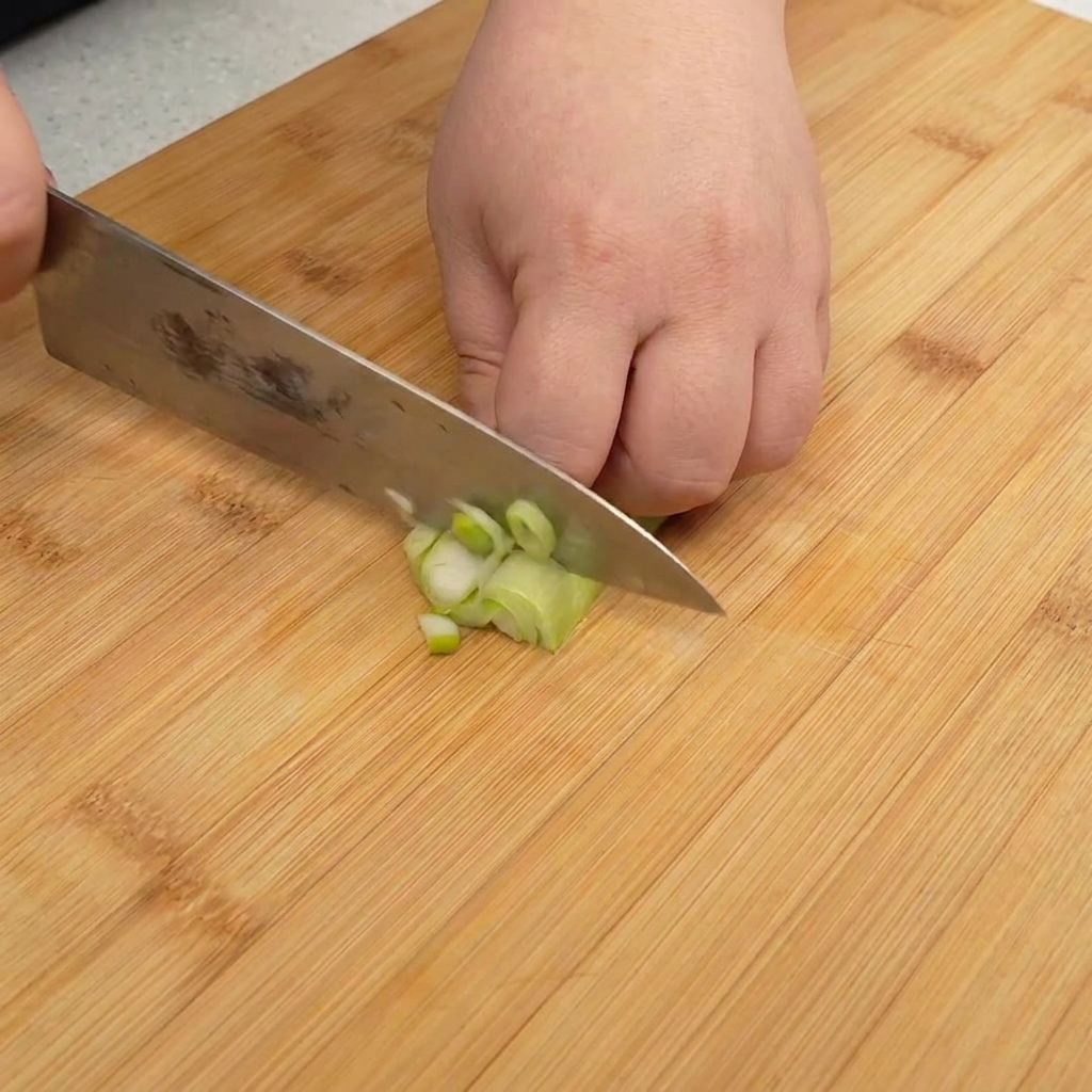 Finely chopped green onions piled on a wooden cutting board, ready for use.