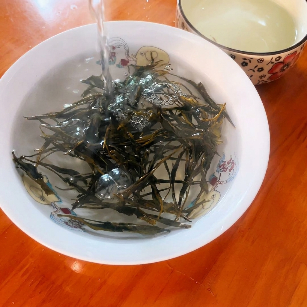 Boiling water being poured over dry green tea leaves in a small decorative bowl.