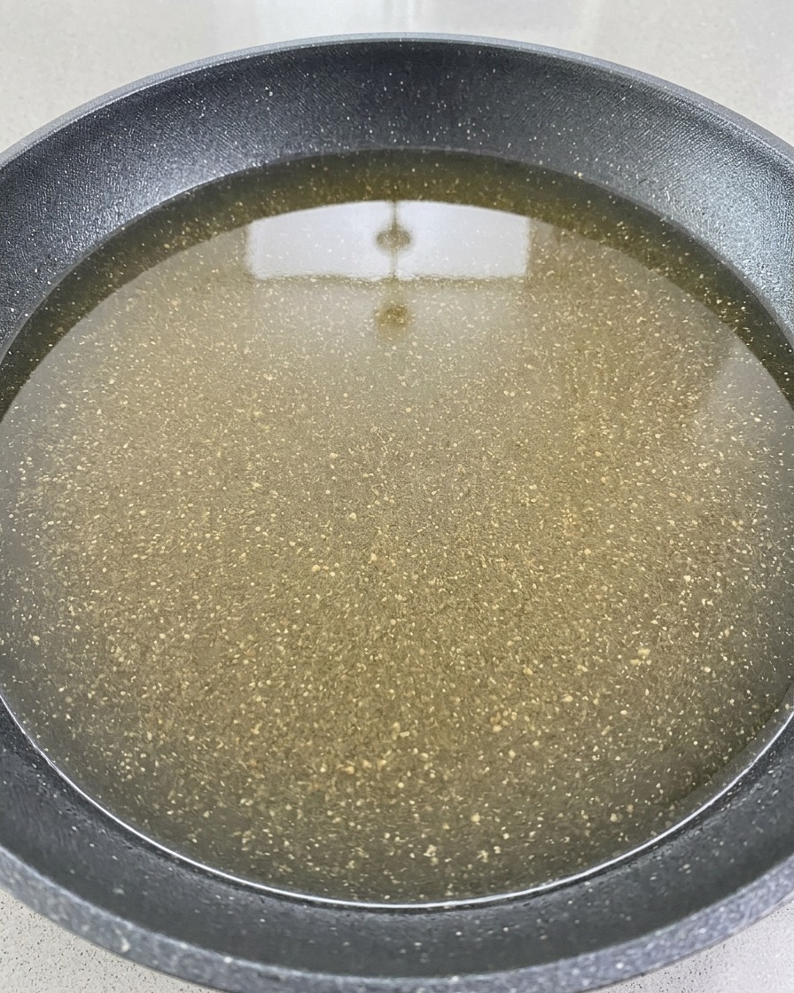 Red wine being poured over the pork and vegetable base in a cooking pot.