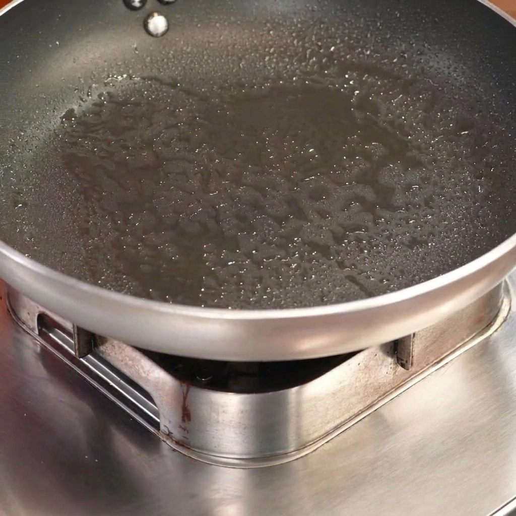 Pork ribs with rice cakes inserted into the center, being seared meat-side down in a hot frying pan.