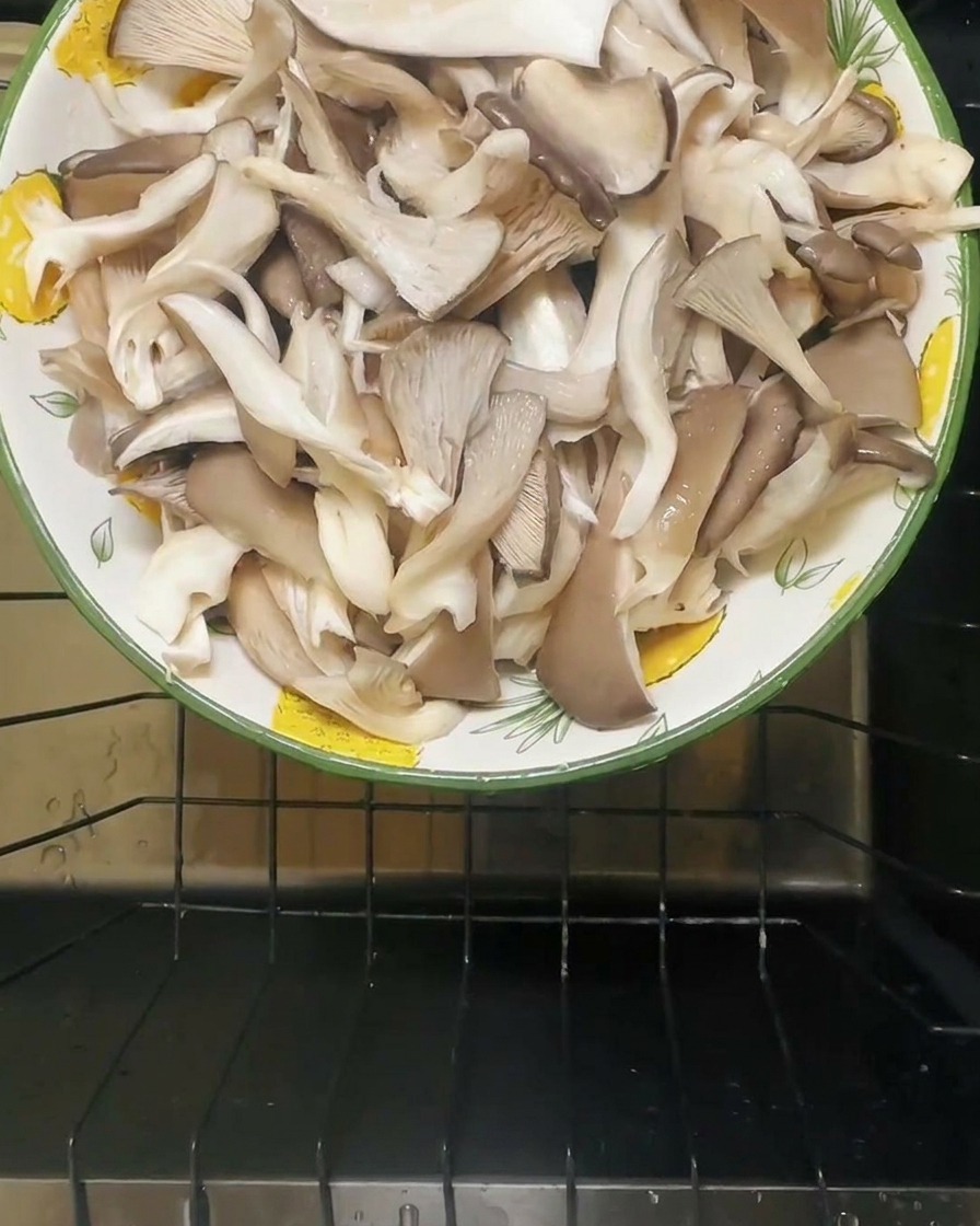 Water being poured into a bowl containing salted oyster mushrooms.
