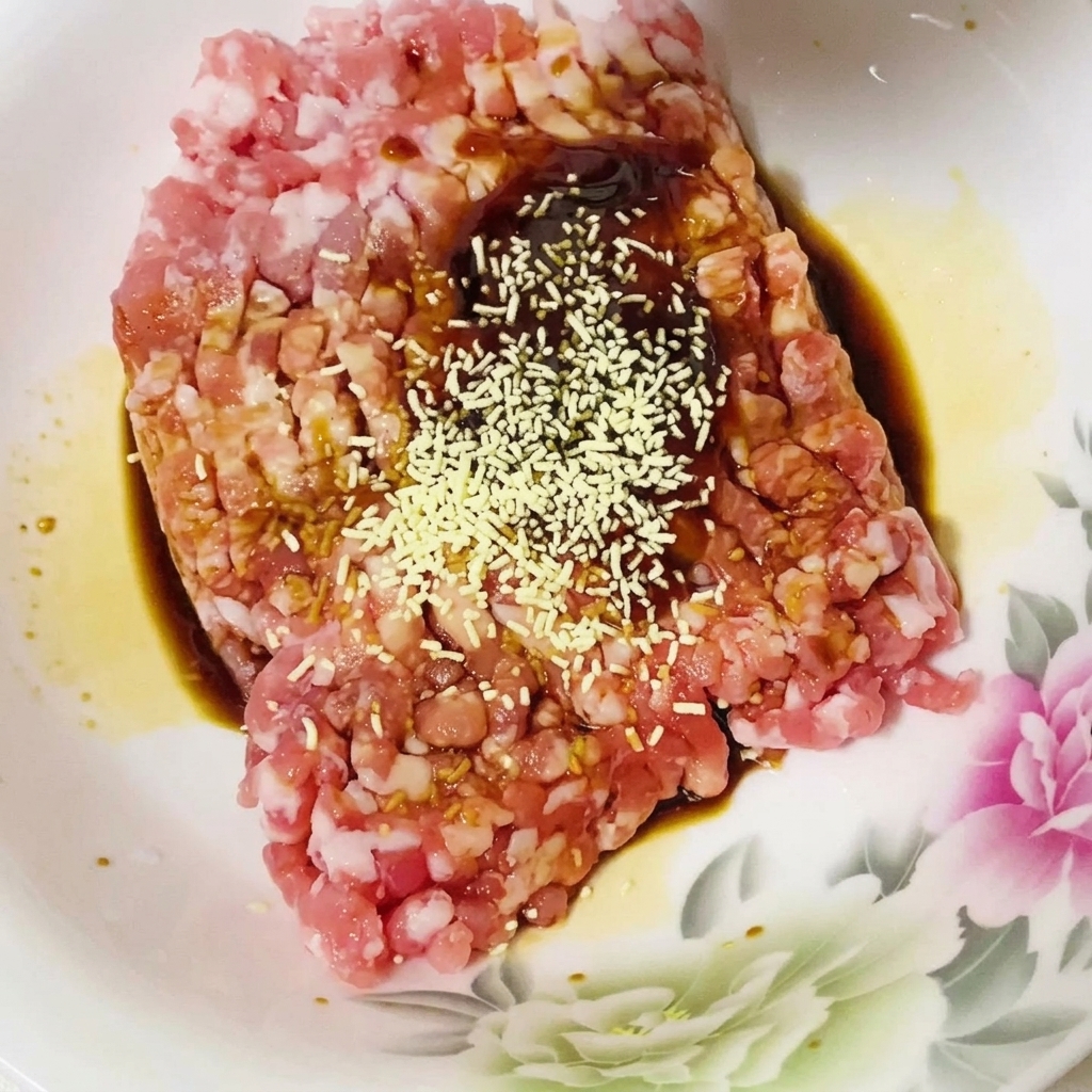 Spices being added to the raw minced pork and sauce mixture.