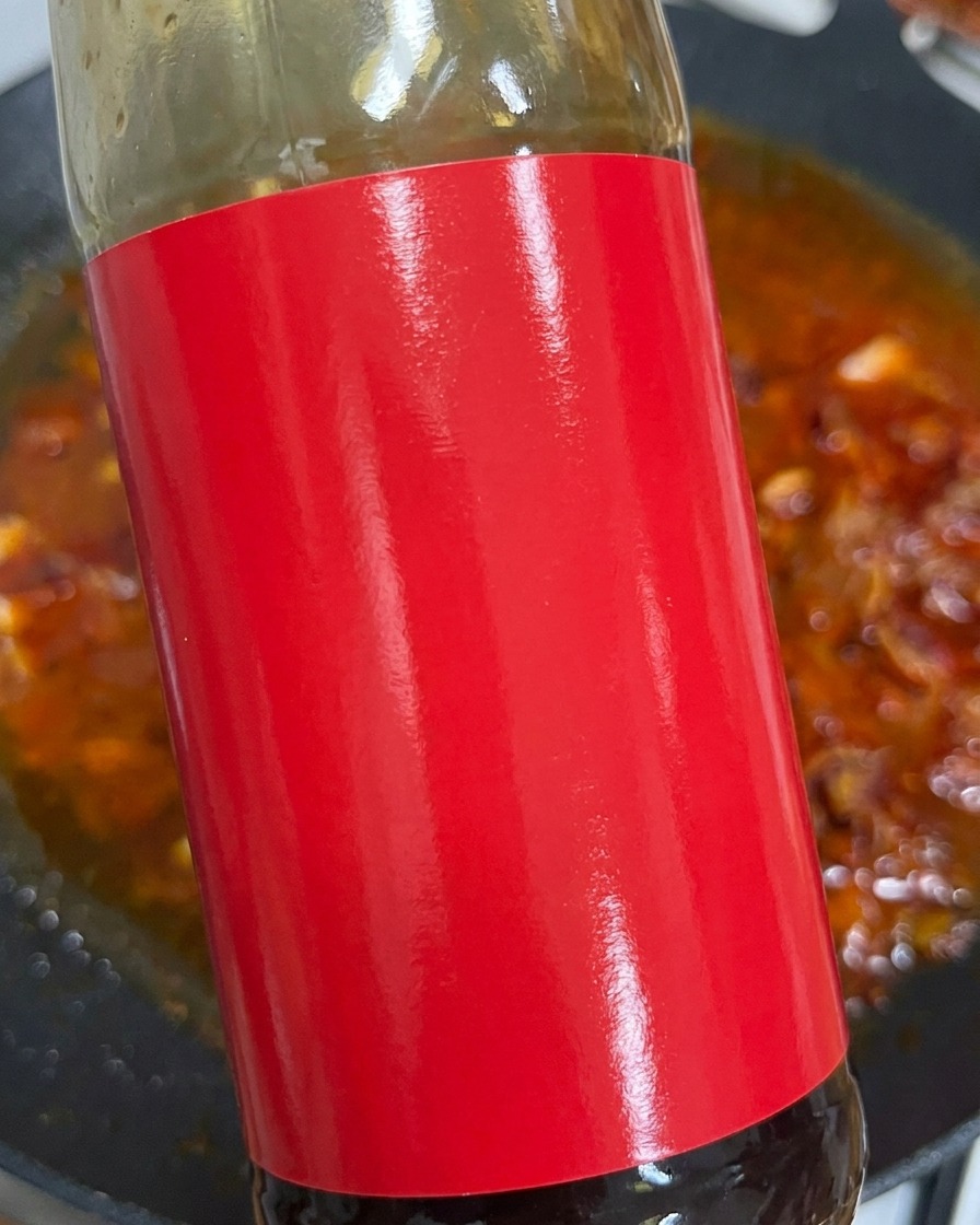 Oyster sauce being squeezed into the red broth.
