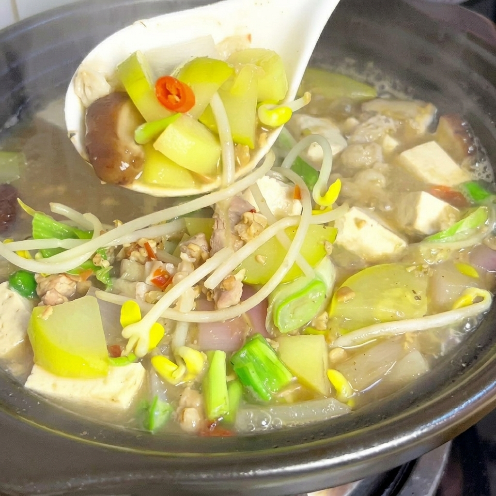 Zucchini wedges and shiitake mushroom slices being dropped into a pot of bubbling broth.