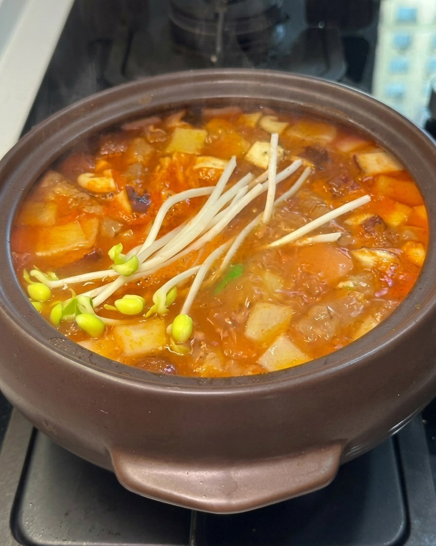 Fresh soybean sprouts added to the top of a bubbling Korean stone pot stew.