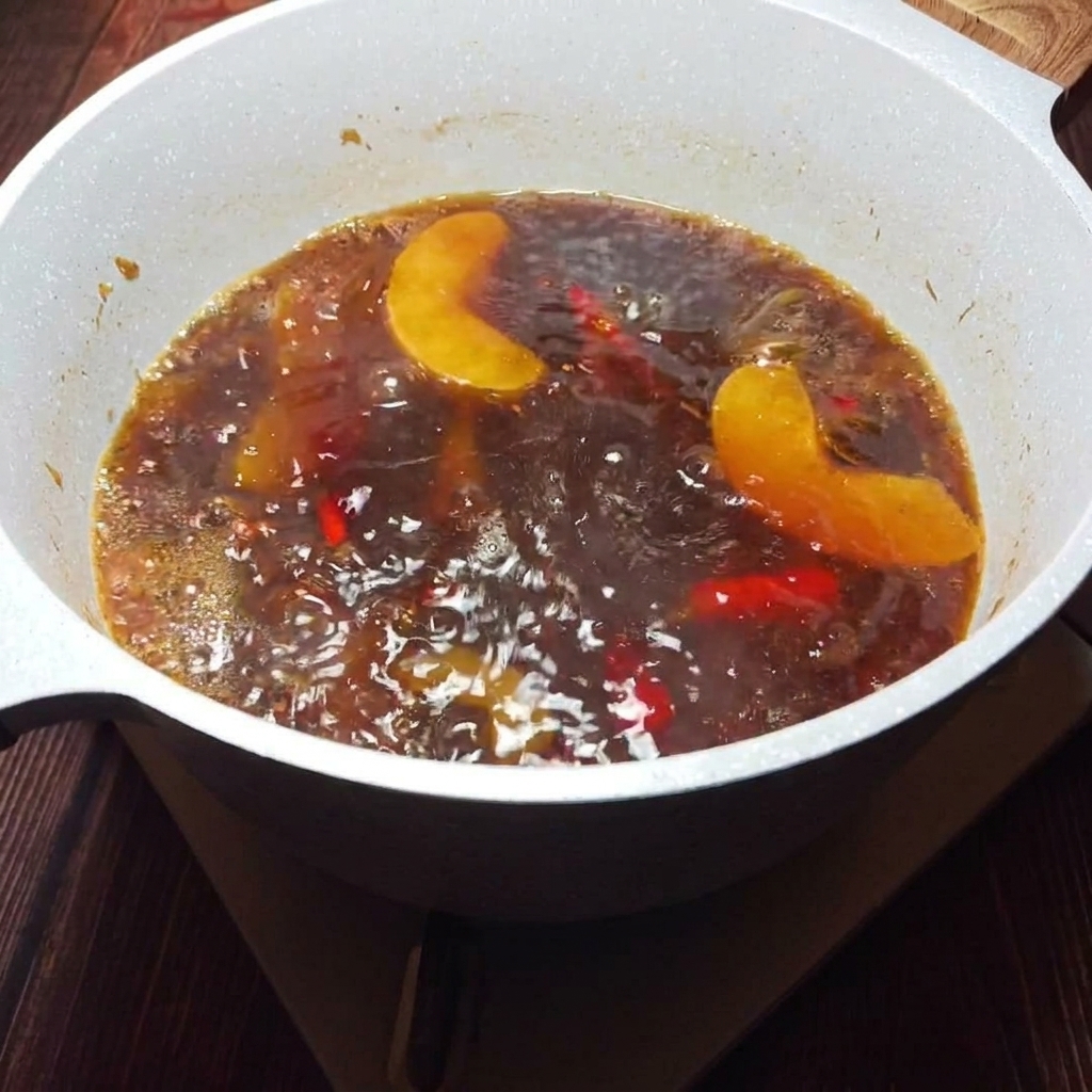 A golden, aromatic broth being strained through a sieve to remove solids.