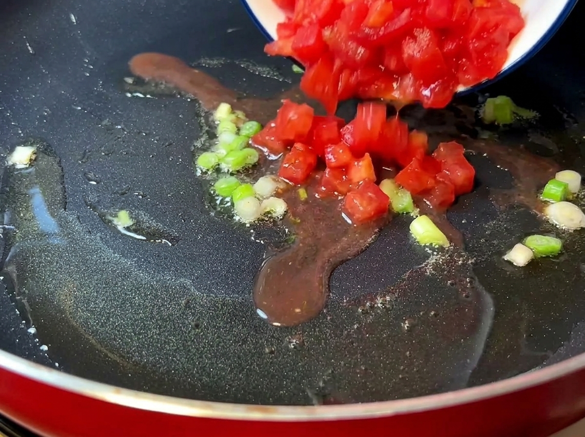 Chopped tomatoes cooking in a pan until soft and juicy.