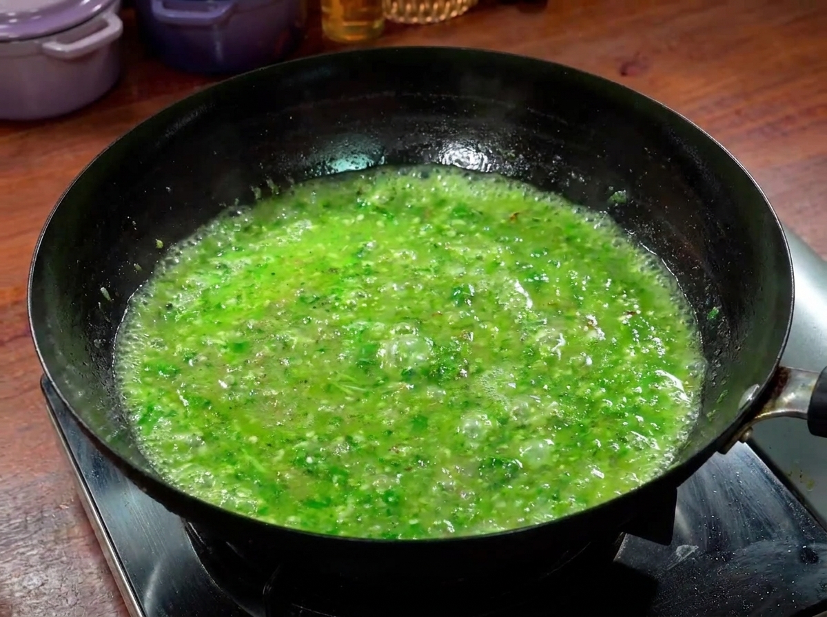 Beef slices cooking in a bubbling, vibrant green spicy broth within a wok.