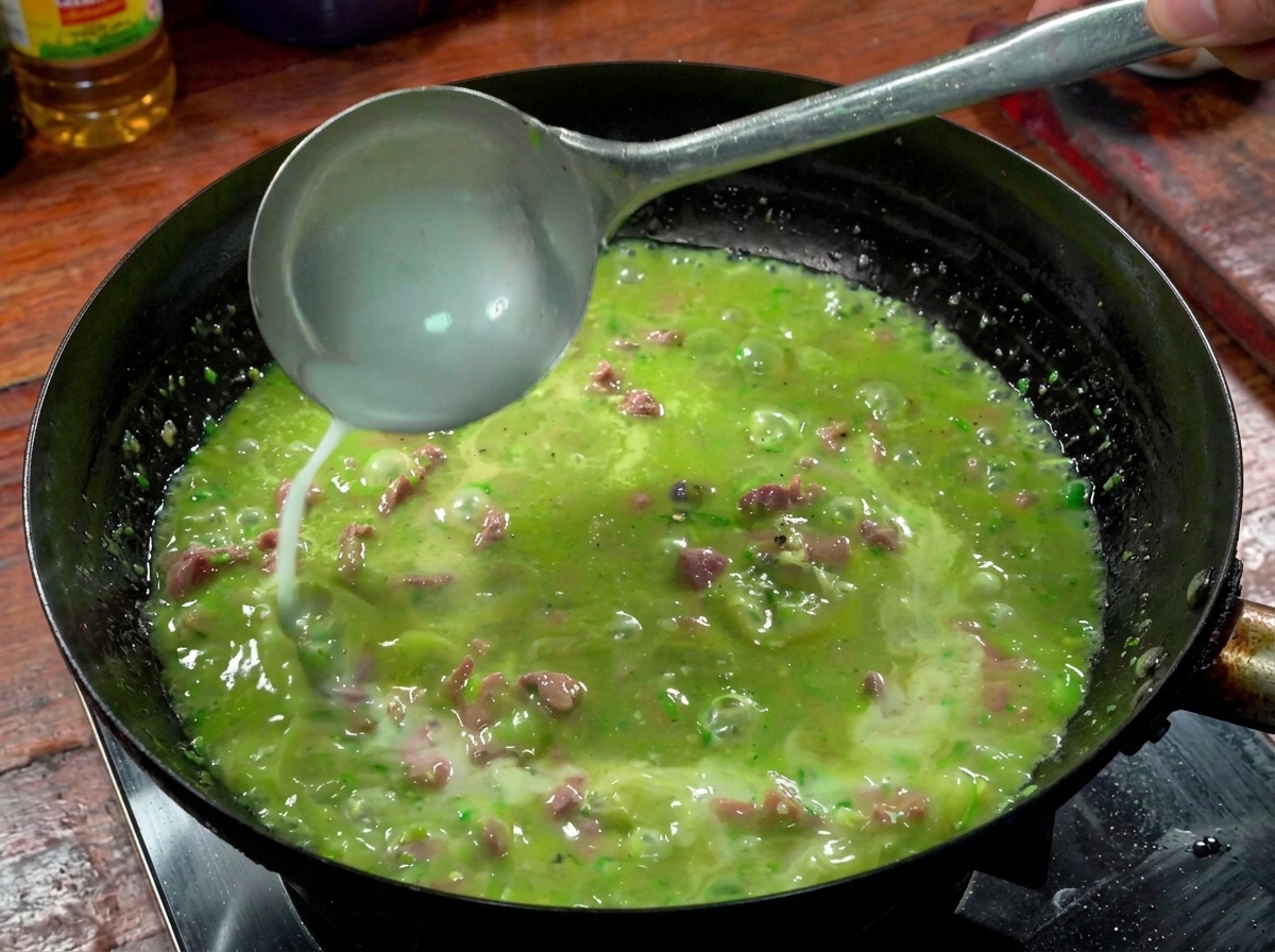 A ladle pouring starch water into the bubbling beef and green chili sauce in a wok.