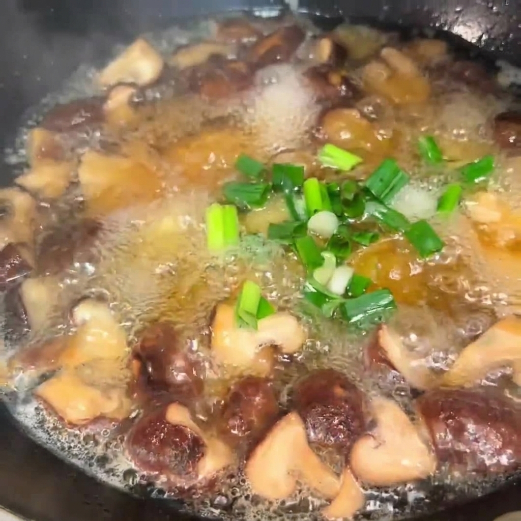 Chopped green onions being sprinkled into a bubbling pot of mushroom and tofu soup.