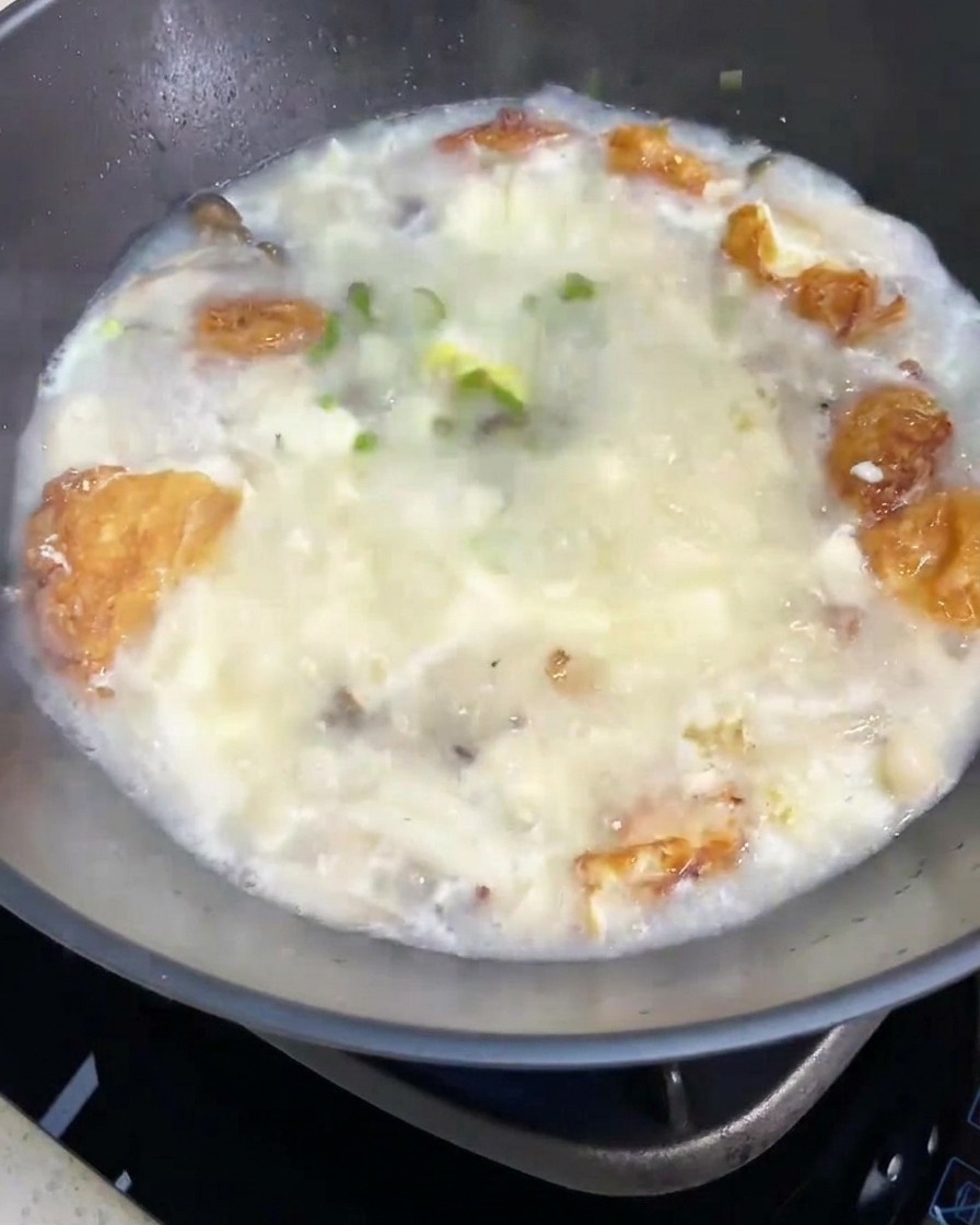 The completed mushroom and tofu soup being garnished with a sprinkle of fresh green onions.