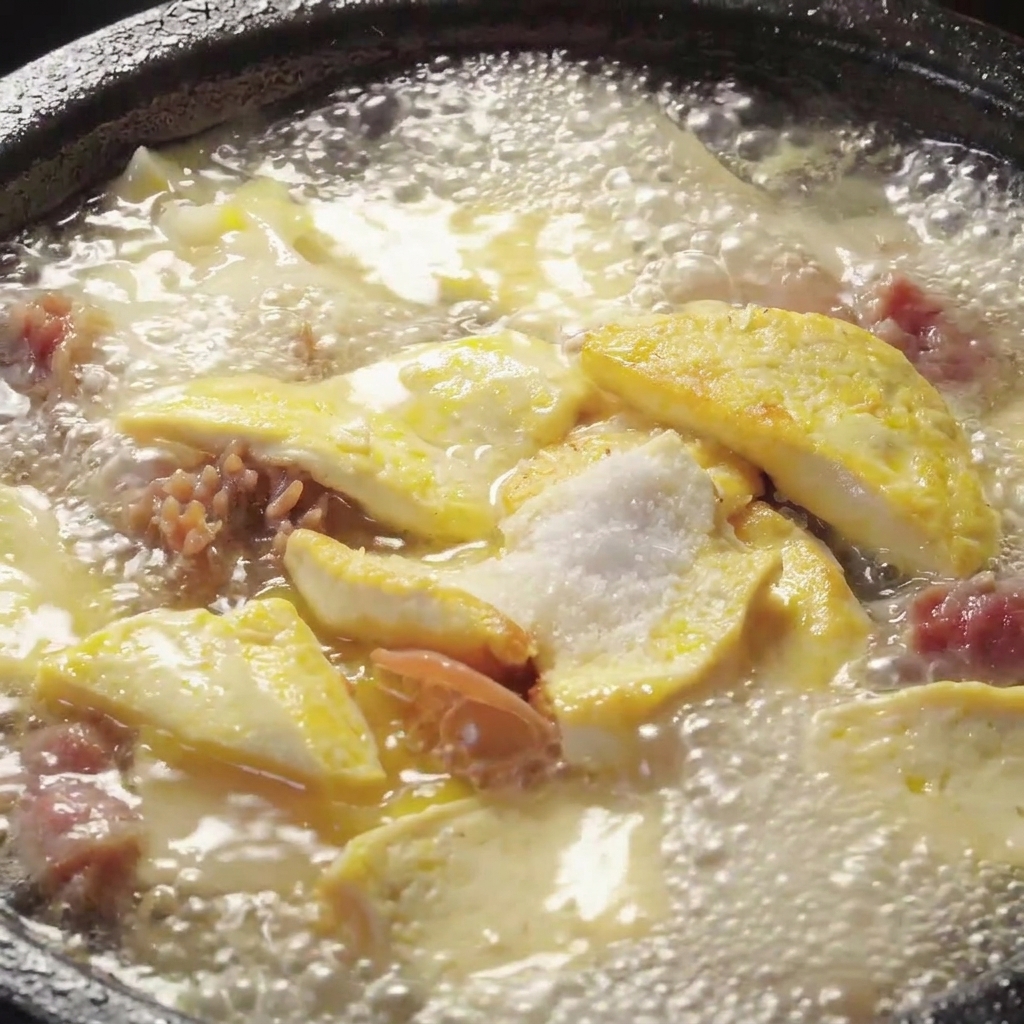 Seasonings being stirred into a bubbling pot of mushroom and tofu soup.