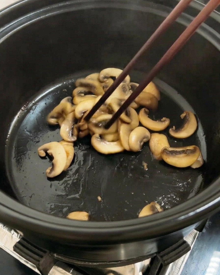 Chopped red tomatoes added to the pot alongside the browned mushrooms, ready to be stir-fried.