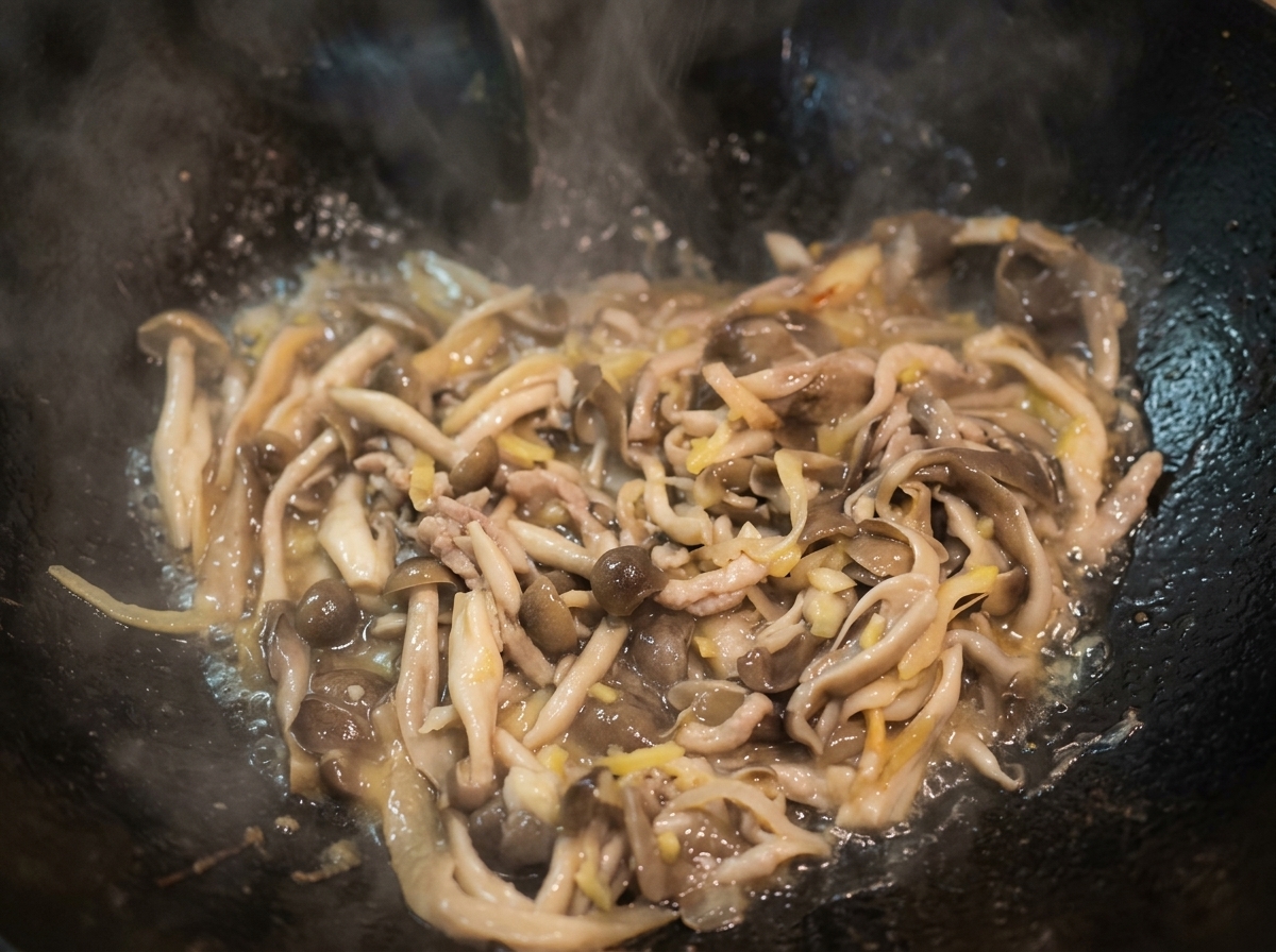 Water boiling in a wok with stir-fried mushrooms, forming a light broth.