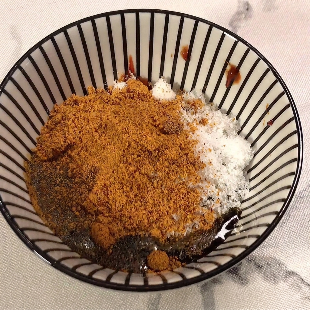 Light soy sauce being poured into the mixture containing chili paste, sugar, and seasoning powder.