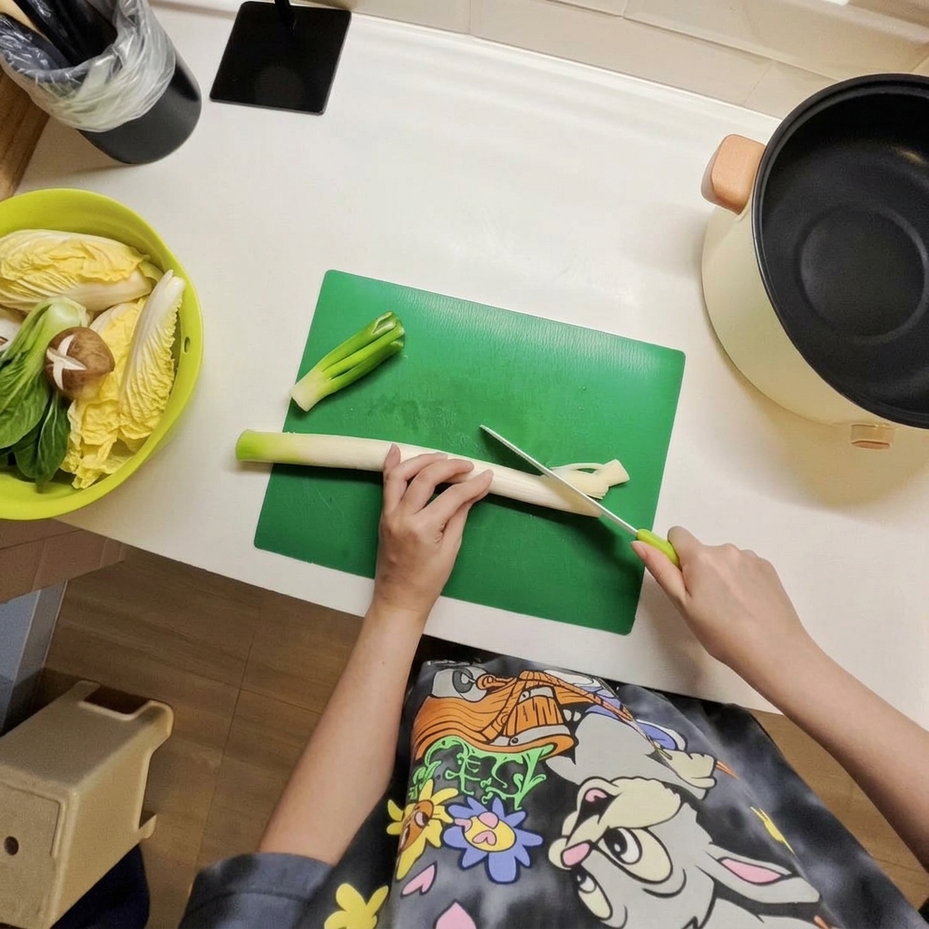 Sliced leeks and chopped napa cabbage being arranged inside an electric cooking pot.
