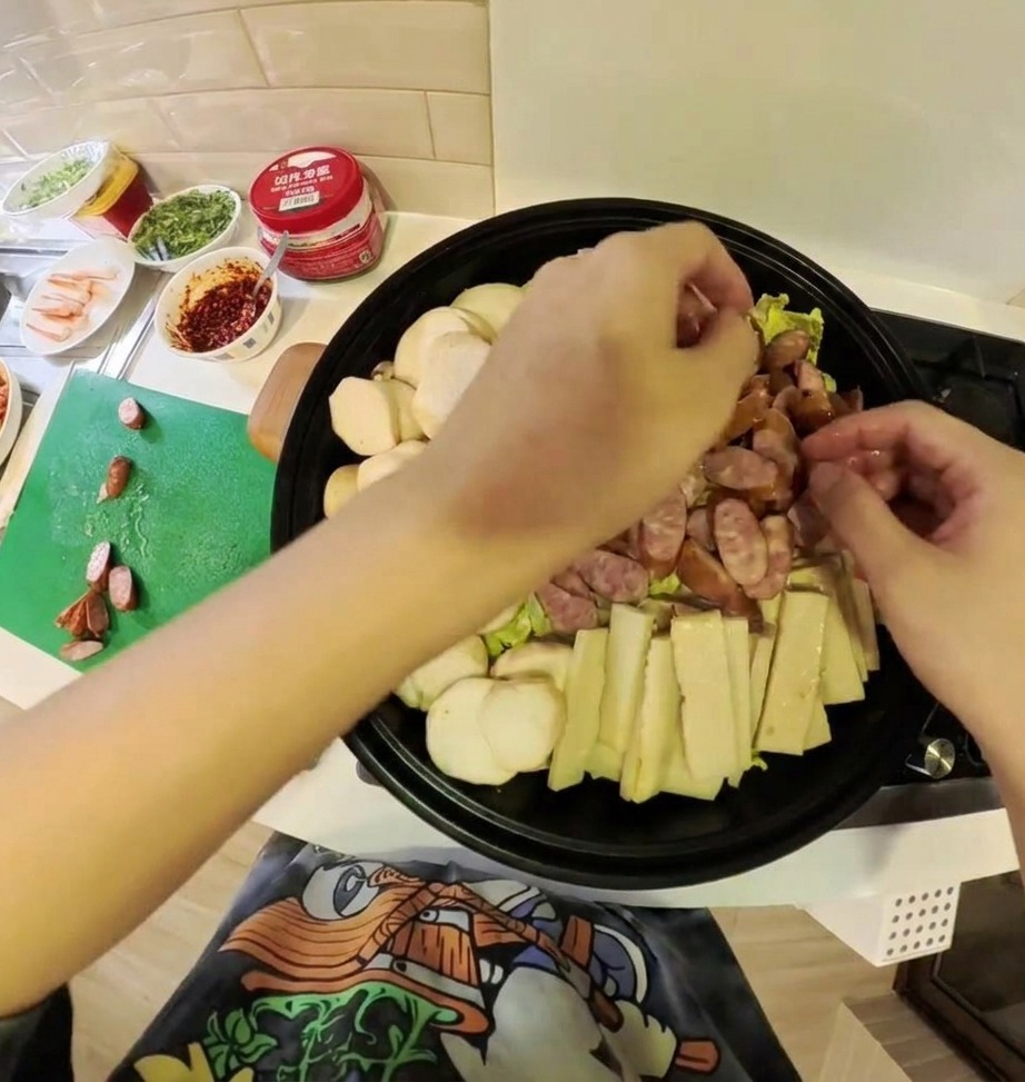 A variety of prepared Korean Army Stew ingredients including kimchi, meat, and vegetables arranged beautifully inside a shallow cooking pot.