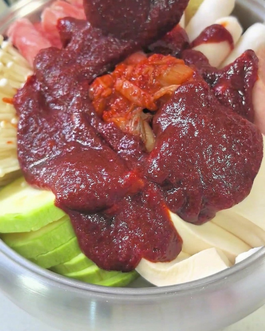 A pot filled with ingredients and broth, covered with a lid, simmering on the stovetop.
