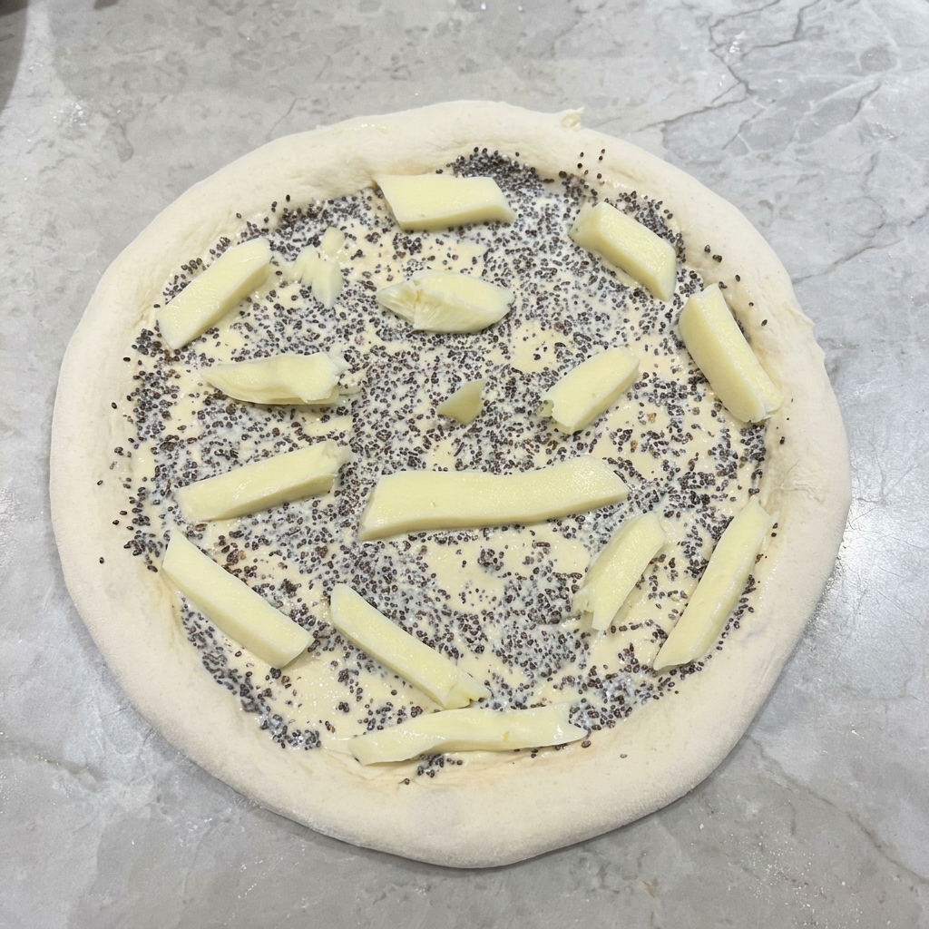 Fresh white mozzarella cheese sticks arranged on top of a truffle-sauce-covered pizza dough.