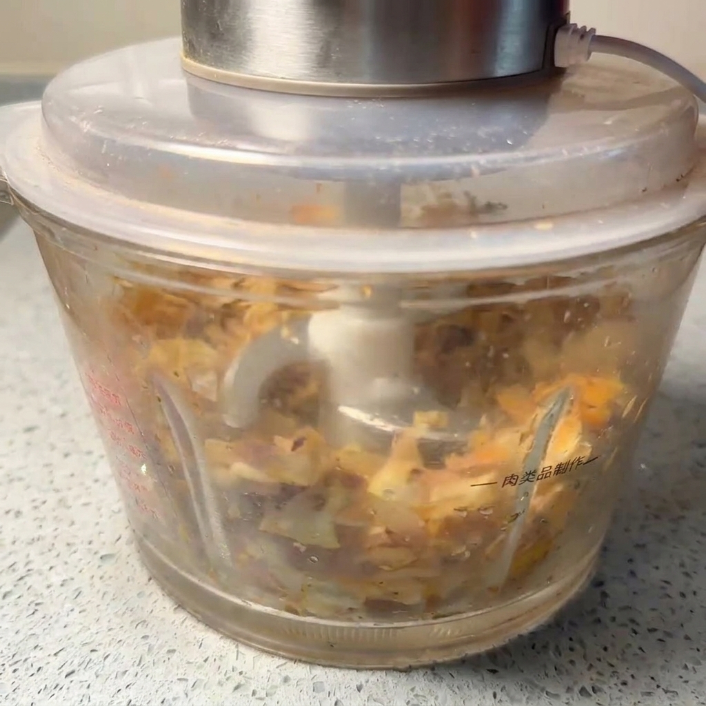 Dried seafood being processed into a fine, textured brown powder inside a kitchen blender.