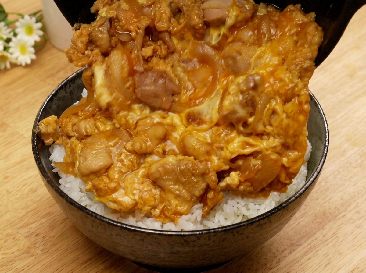 A pan being tilted to allow the cooked Oyakodon mixture to slide onto a bowl of white ricecite: 4.