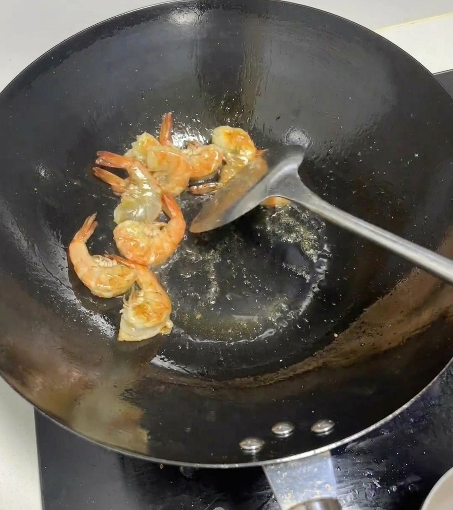 Whole shrimp turning bright pink as they are stir-fried in a hot wok.