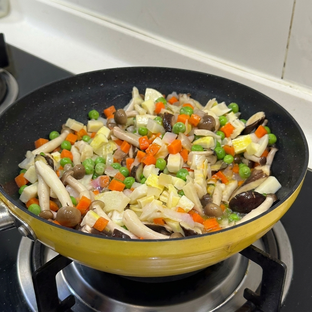A colorful mix of diced vegetables and mushrooms being stir-fried together in a yellow pan.