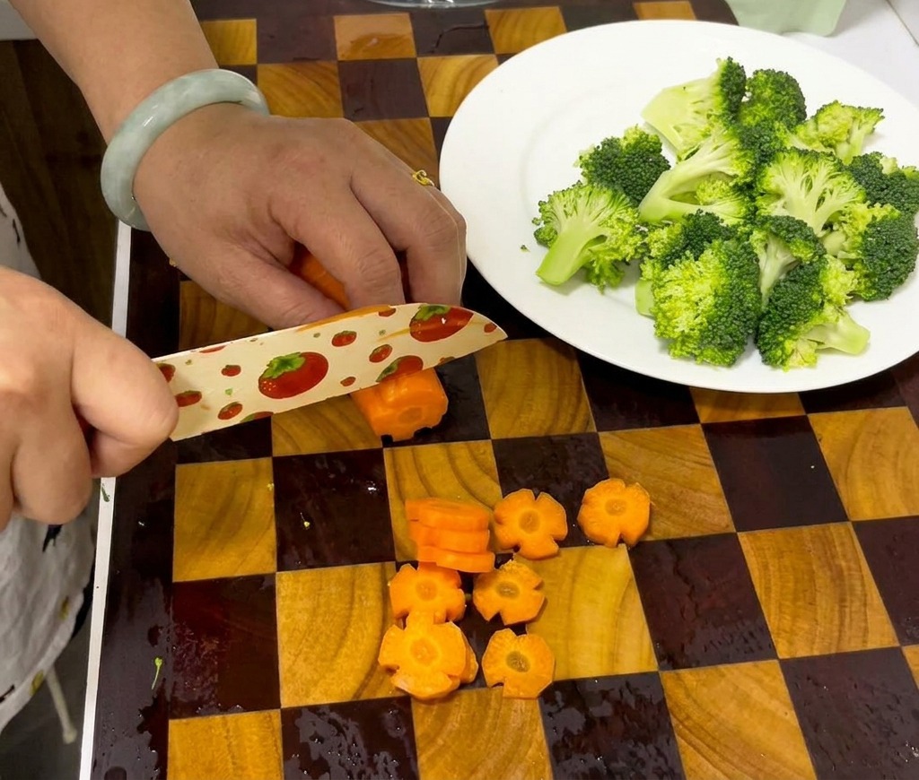 Hands using a knife to slice a grooved carrot into decorative flower-shaped discs on a cutting board.