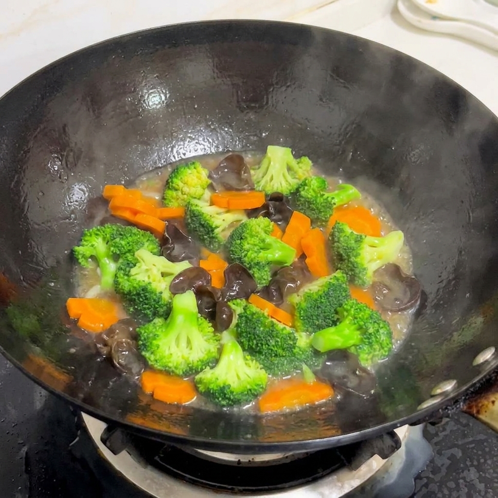 A colorful mix of broccoli, carrots, and wood ear mushrooms being stir-fried in a wok with a glossy sauce.