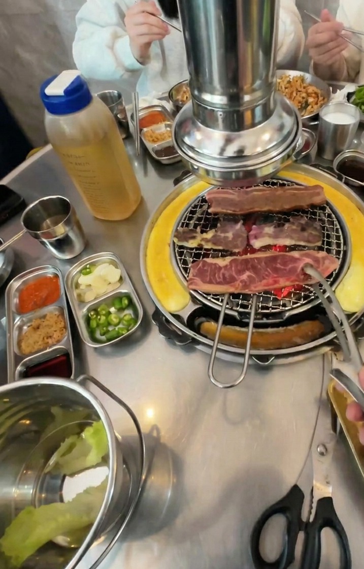 Beef strips being flipped on a charcoal grill, showing a deeply browned and caramelized exterior.