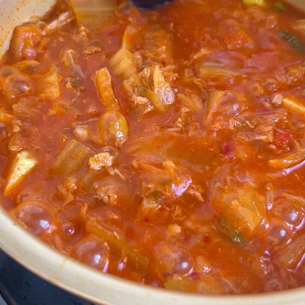 Small pink cubes of diced ham being sautéed and browned on a flat black cooking surface.