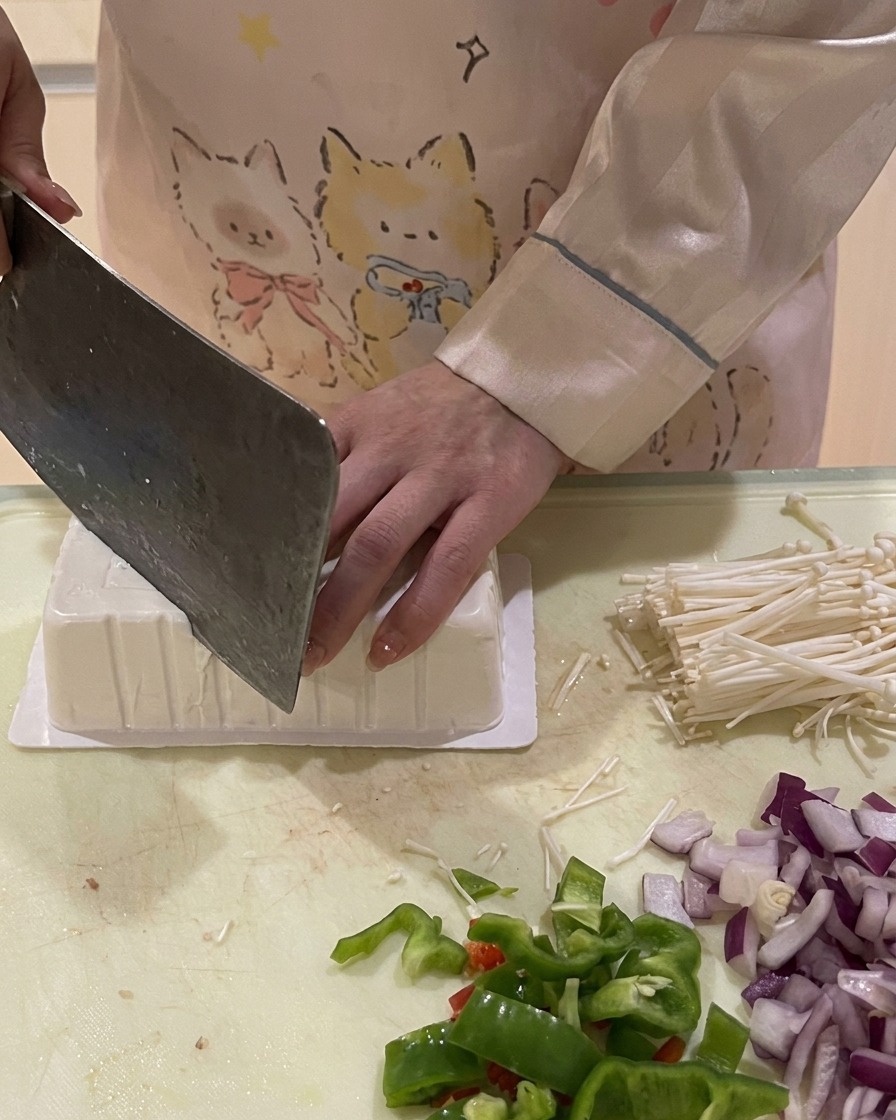 A knife cutting the corner of an inverted tofu box to let air in for easy removal.
