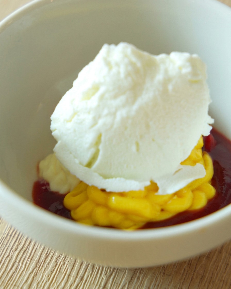 A white ceramic bowl containing a creamy orange-colored burger sauce being stirred until smooth.